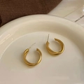 Pendientes de aro dorados retorcidos minimalistas sobre un elegante plato de cerámica - Dorado