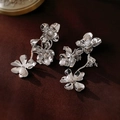 Detalle de aretes de flores plateadas con perlas sobre fondo de terciopelo rojo - Pendientes colgantes de flores plateadas y perlas (Perno de plata de ley 925)