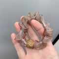 Detailansicht eines braunen Netz-Haargummis mit einer funkelnden Strass-Dekokugel - Organza Lila
