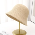 Close-up of beige woven bucket hat showing fine knit texture on a gold metal stand - Beige
