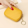Yellow textured leather mini wallet with gold chain and keychain held by a hand - Yellow
