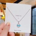 Détail du pendentif planète avec pierre bleu clair sur une chaîne fine argentée élégante - Planète Eau de Source