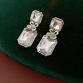Detalle macro de pendientes cuadrados de cristal plateado con lazos metálicos finos - Pendientes-Pin de Plata Plata