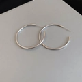 Flat lay of large minimalist silver hoop earrings on a light gray background - 4cm / Silver / Silver Needle