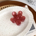 Close-up of a translucent red flower hair claw clip on a stylish ceramic plate - Rose Red