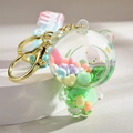 Close-up of bear-shaped liquid keychain with pink beads and glitter inside the bubble - Gradient Strap + Bear / Green