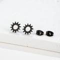 Close-up of minimalist black matte sunburst stud earrings on white marble stand - Sun / Black