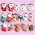 Flat lay of colorful resin Santa, reindeer, and Christmas tree charms on pink wood - Mixed Colors