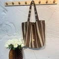 Brown and beige striped woven tote bag with a handmade metal tag on a wooden hook - Brown Striped Vertical Shoulder Bag