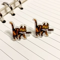 Quirky acrylic tortoiseshell cat earrings with knife design on striped notebook background - Tortoiseshell Cat With Knife