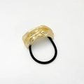 Detalle del adorno dorado de metal fundido irregular en gomilla de pelo negra - Dorado