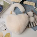 Close-up of heart-shaped faux fur bag with plush pom-poms and golden chain strap - Off-white