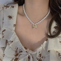 Collier de perles blanches vintage avec pendentif nœud doré porté sur un modèle - Style Perle Noeud (HN1976)