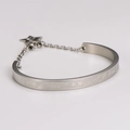 Detalle de brazalete de acero inoxidable plateado con relieve de estrella y colgante - Color Acero