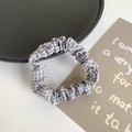 Elastic gray and white checkered fabric scrunchie with soft pleats on a black plate - Grey Grid