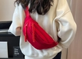 Red crossbody chest bag with braided zipper pulls worn over a white knit sweater - Red