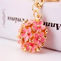 Detail van een roze emaille bloemen sleutelhanger met gouden metalen bloemblaadjes - Roze