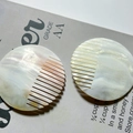 Natural iridescent seashell hair combs in cream and pearl white on an open book - Round Comb