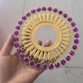 Detail of gold sunburst wall decor with purple rhinestones held in a hand - Gold Purple Zirconia