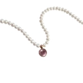 Close-up of white pearl necklace with round pink birthstone pendant in gold setting - October Tourmaline