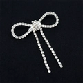 Elegant silver bow brooch with dangling rhinestones on a black textured fabric background - Tassel Bowknot