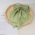 Elegant sage green oversized satin bow hair clip with long streamers on beige tray - Matcha Green