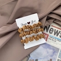 Set of three satin scrunchies in bronze and brown colors on a white display card - Tan