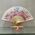 Traditional Chinese folding fan with pink cherry blossoms, wooden stand, and tassel - Peach Blossom
