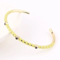Détail du bracelet émaillé à rayures dorées et jaunes avec texture en spirale et points noirs - Jaune