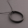 Detail of black leather punk bracelet featuring metallic rivets and adjustable cord closure - Gunmetal