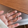 Detailed view of silver twisted geometric hoop earrings held against a wooden background - Large Round Hoop 50mm (Silver Earring Post)