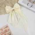Macro view of creamy white satin oversized bow hair clip on a minimalist lace background - Off White