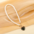Dettaglio della collana di perle con ciondolo a cuore verde scuro e chiusura a T d'oro - Grigio