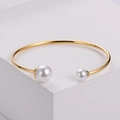 Elegant gold open cuff bracelet with two asymmetric white pearls on a white stand - Gold