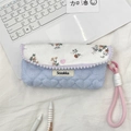 Detail of floral pencil case with heart button and pink rope handle on laptop keyboard - Orange Floral + Blue Stripes