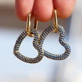 Orecchini a cuore placcati oro 18 carati con zirconi blu mostrati nella mano - Blu