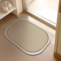 Oval beige diatom mud bath mat with dark brown border on a modern wooden floor - Diatom Mud - Su Jin-A