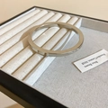 Detailed macro view of a silver polished flat rectangular bangle on a fabric tray - Silver