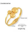 Detail of gold-plated titanium steel bangle showing metal balls and inner diameter size - Gold