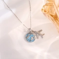 Macro shot of silver airplane and light blue globe pendants on a stylish chain - Silver Earth Airplane Style