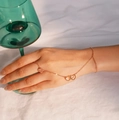Catena da mano in oro rosa con anello a cuore e bracciale indossata su lino bianco - Cuore a cuore dorato