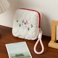 Gros plan d'un mignon chien brodé sur une trousse à maquillage matelassée blanche - Chiot fleur