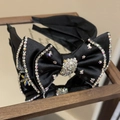 Dettaglio di un cerchietto di lusso in raso nero con fiocco di strass e grappoli di cristalli - Nero