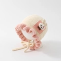 Detailed close-up of knitted baby bonnet with pink ruffle trim and rabbit patch - 50cm 1-2 Years / Rabbit-Beige