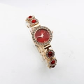 Detailed macro view of gold quartz watch featuring red dial with sparkling rhinestones - Red