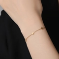 Elegant gold double-layered four-leaf clover bracelet on model wrist with black background - Clover Style (XKB0261) - Gold