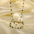 Golden necklace with green emerald beads displayed on elegant beige silk fabric - Yysu024055