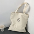 Detail of minimalist cream canvas tote bag with black smiley face print and sturdy handles - Beige Smile