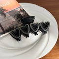 Elegant black acetate hair claw clip with four hollow grey heart shapes on a white plate - Black