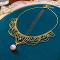 Detail van Franse kanten parelketting op groen fluweel en een sierlijk gouden dienblad - Ketting - Goud